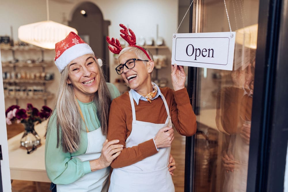 Business owners smiling and wearing holiday clothing opening the business for the day