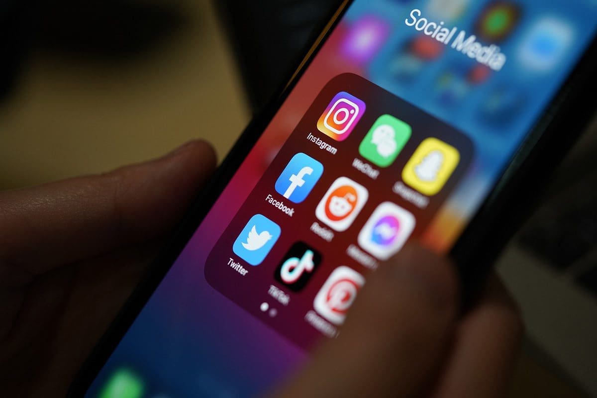 Phone screen showing social media apps including Facebook Instagram TikTok and Snapchat