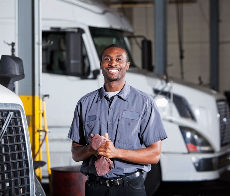 Mechanic smiling and standing in front of semi trucks